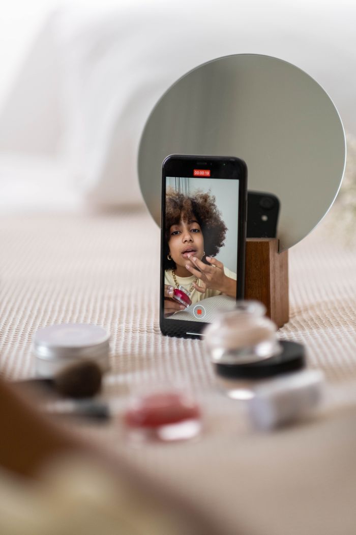 services-02 A beauty influencer vlogs a makeup tutorial using a smartphone indoors.